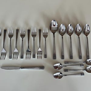Puede incluir: Un juego de cubiertos, que incluye tenedores, cucharas y un cuchillo. Los cubiertos están hechos de acero inoxidable y tienen un acabado pulido.