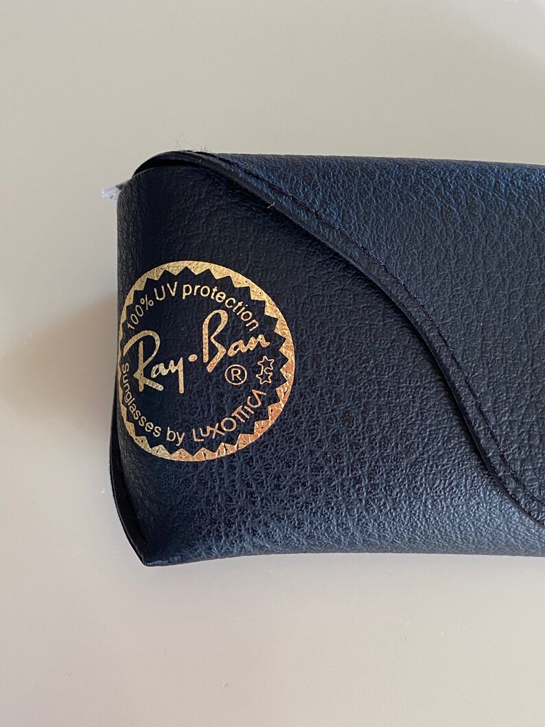 May include: A black leather case with a gold Ray-Ban logo that reads "100% UV protection Sunglasses by Luxottica".