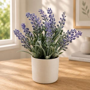 May include: A potted artificial lavender plant featuring vibrant purple flower spikes and soft green foliage. The plant is housed in a simple, matte white cylindrical ceramic pot, creating a clean and balanced display of botanical decor.