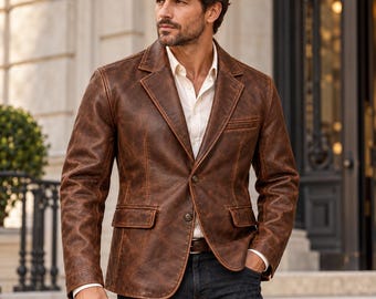 May include: A brown leather blazer with a distressed finish, featuring a notched lapel, two front buttons, and two flap pockets. The blazer is worn over a crisp white button-down shirt and dark denim jeans, creating a structured and layered look.