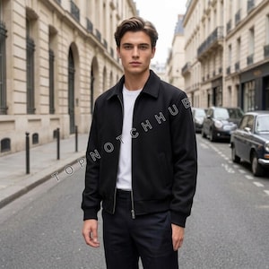 May include: A black zip-up jacket with a classic collar and ribbed cuffs worn over a plain white t-shirt and dark trousers. The jacket features a clean, structured design with a central zipper closure and side pockets. The text TOPNOTCHHUB is visible.