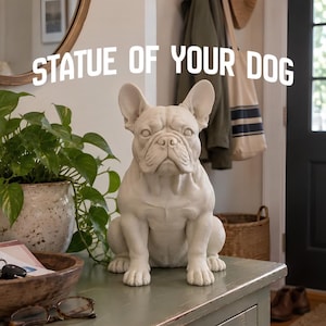 May include: A matte off-white French Bulldog statue in a seated position with upright ears and a detailed facial expression. The text "STATUE OF YOUR DOG" is displayed in white capital letters above the dog figure, which is positioned on a surface.
