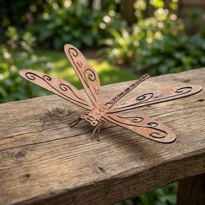 Può includere: Una scultura di libellula in metallo con una finitura marrone arrugginita e usurata. Le ali presentano intricati motivi geometrici e a spirale ritagliati. Il corpo è allungato con dettagli segmentati e le ali sono spiegate in posizione orizzontale.