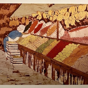 May include: A batik art print depicting a market scene with a person in a blue shirt and white apron standing beside stacked wooden crates. The stall features rows of colorful produce, including yellow bananas, red spices, and various fruits in baskets.
