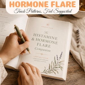 Peut inclure: Un agenda ouvert intitulé The Histamine & Hormone Flare Companion avec un stylo vert posé sur la page. La page de couverture présente du texte, un petit emblème floral et une illustration botanique de brins de lavande en bas à droite.