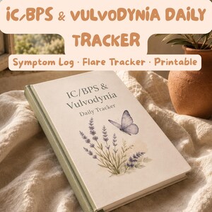 May include: A daily tracker book with a cream cover featuring a lavender sprig illustration, a butterfly, and the text IC/BPS & Vulvodynia Daily Tracker. The book has a green spine and a ribbon bookmark, presented with a soft textured fabric.