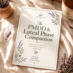 Peut inclure: Un agenda rectangulaire intitulé The PMDD & Luteal Phase Companion par Chronic Calm. La couverture blanche présente un texte vert foncé, des accents dorés et des illustrations à l'aquarelle de brins de lavande. Le texte indique : A gentle cycle-aware planner for mood, symptoms, energy, care, and hard days. Track gently. Notice patterns. Feel more prepared.