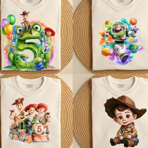 May include: Four off-white t-shirts featuring colorful Toy Story character graphics. One shows a large green number five with Woody, Jessie, and aliens. Another features Buzz Lightyear with planets. A third shows characters on a train. One shows a young cowboy.