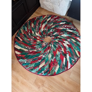 May include: A circular Christmas tree skirt featuring a patchwork design of diagonal fabric strips in shades of deep red, forest green, and gold. The fabric patterns include floral motifs, holly leaves, and geometric textures with a solid red border.