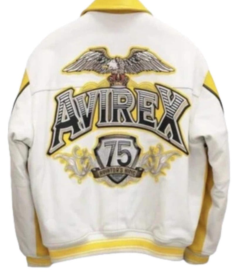 May include: A white and yellow jacket featuring a large embroidered eagle graphic above the text AVIREX. Below the text is a shield emblem with the number 75 and the words AVIATOR'S KING. The jacket has a yellow collar, yellow side panels, and yellow ribbed cuffs.