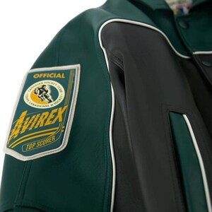 May include: A dark green and black leather jacket featuring white piping accents. A rectangular patch on the sleeve displays the text OFFICIAL, CANADIAN HOCKEY TEAM, AVIREX, and TOP SCORER, along with a graphic of a hockey player in a circular frame.