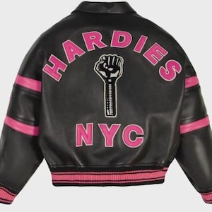 Peut inclure: Une veste universitaire en cuir noir avec des accents ray&eacute;s roses sur les manches et l'ourlet. Le dos pr&eacute;sente le texte HARDIES dans une police rose arqu&eacute;e, un graphique d'un poing lev&eacute; avec un d&eacute;tail de fermeture &eacute;clair et le texte NYC en lettres roses.