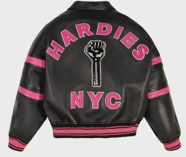 Peut inclure: Une veste universitaire en cuir noir avec des accents ray&eacute;s roses sur les manches et l'ourlet. Le dos pr&eacute;sente le texte HARDIES dans une police rose arqu&eacute;e, un graphique d'un poing lev&eacute; avec un d&eacute;tail de fermeture &eacute;clair et le texte NYC en lettres roses.