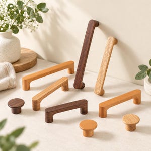 May include: A collection of wooden cabinet hardware including several rectangular bar pulls and round knobs in various wood tones ranging from light oak to dark walnut, featuring smooth finishes and simple, functional geometric shapes.