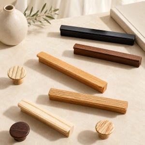 May include: A collection of cabinet hardware including four rectangular wooden drawer pulls in varying light, medium, and dark wood tones, one black rectangular pull, and three round wooden knobs in light and dark wood finishes.