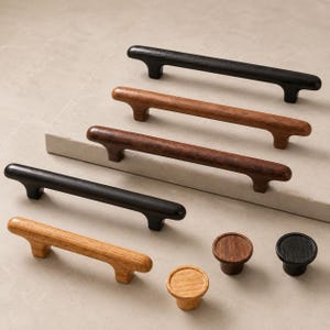 Puede incluir: Una colecci&oacute;n de herrajes de madera para muebles que incluye cuatro tiradores alargados y tres pomos circulares. Los art&iacute;culos presentan varios acabados de veta de madera en tonos roble claro, nogal medio y negro con bordes redondeados.