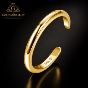 May include: A polished gold-tone open ring with a smooth, rounded band. The interior of the band features the stamped text 14K GF. The ring is presented against a dark background with the Goldsmith Mart logo visible in the upper left corner.