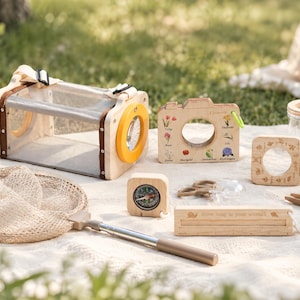 Puede incluir: Un kit de exploración de la naturaleza de madera que incluye un hábitat de malla para insectos con lente amarilla, una herramienta de identificación de flores con forma de cámara, lupa, brújula, red con mango telescópico, frasco, pinzas y regla.