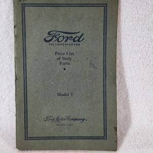 May include: A vintage olive green booklet titled Ford The Universal Car Price List of Body Parts Model T, featuring the Ford Motor Company Detroit, Mich logo. The cover has a dark blue rectangular border and dark blue printed text throughout.