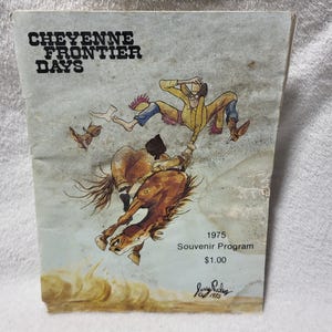 May include: A 1975 Cheyenne Frontier Days souvenir program featuring a cartoon illustration of a cowboy being bucked off a brown horse. The cover includes the text Cheyenne Frontier Days, 1975 Souvenir Program, and a signature by Jerry Palen.