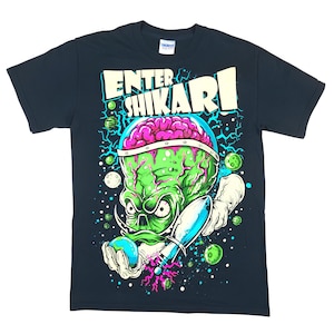 May include: A black short-sleeve t-shirt featuring a graphic print of a green alien with a pink brain inside a glass dome. The alien holds a small globe and a blue rocket. The text ENTER SHIKARI is printed in large white letters above the alien.