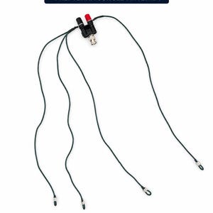Puede incluir: Una antena Preptenna Jungle que presenta un bloque conector central negro con un terminal rojo y uno negro, un conector BNC plateado y cuatro cables largos de color verde oscuro que se extienden hacia afuera, terminando en un pequeño bucle metálico.