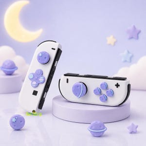 May include: Two white game controllers featuring light purple silicone thumbstick covers and button caps. The covers are shaped like planets and stars. The controllers have black side rails and buttons. The text RetroGrip is visible in green.
