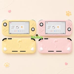May include: Two handheld gaming consoles with protective cases in pastel yellow and light pink. The cases feature embossed cat tail and paw designs. The screens display a menu with cat icons. The text RetroGrip is visible in the center.