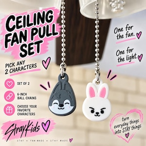 May include: A ceiling fan pull set featuring two character charms on 15.24 cm ball chains. One charm is a grey wolf-like face, and the other is a white rabbit-like face with pink ears. Text includes CEILING FAN PULL SET, PICK ANY 2 CHARACTERS, SET OF 2, 6-INCH BALL CHAINS, CHOOSE YOUR FAVORITE CHARACTERS, StrayKids, and turn everyday things into STAY things.