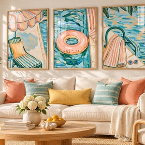 May include: A set of three framed art prints depicting a swimming pool scene with a lounge chair under a pink umbrella, a pink pool float, and a striped towel draped over a pool ladder, all rendered in a painterly style with blue and pink tones.