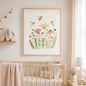 May include: A framed wall art print featuring a watercolor illustration of a wildflower meadow with various colorful flowers in shades of pink, yellow, and blue, accompanied by three small flying fairies with delicate wings and simple dresses.