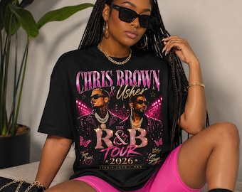 May include: A black short-sleeve t-shirt featuring a graphic print of Chris Brown and Usher with the text The R&B Tour 2026. The design includes pink and gold accents, stars, butterflies, and a crown motif set against a dark background.