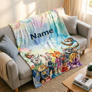 May include: A soft throw blanket featuring a watercolour-style background with pastel bubbles and the word Name printed in dark blue. The blanket displays a colourful group of animated animal characters including a rabbit, fox, and sloth.