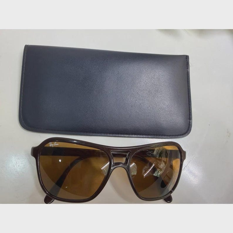 Puede incluir: Gafas de sol de color marr&oacute;n oscuro con doble puente y lentes tintadas en &aacute;mbar, con el logotipo de Ray-Ban en la lente superior derecha. Las gafas vienen acompa&ntilde;adas de un estuche protector rectangular negro de textura lisa.