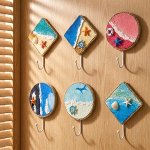 Peut inclure: Six patères murales ornées de plaques décoratives sur le thème marin. Les plaques, circulaires ou en forme de losange, présentent des scènes de plage texturées avec des étoiles de mer, coquillages, bouées et gouvernails miniatures.