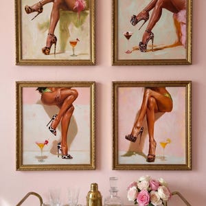 Set of four cocktail wall art prints in gold frames above a styled bar cart with pink flowers and glassware, leopard heel and martini art