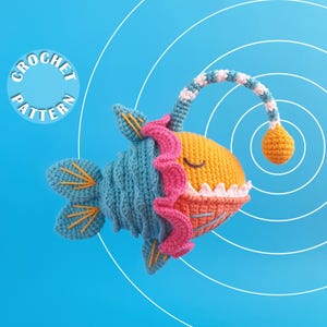 Peut inclure: Un jouet poisson-pêcheur au crochet avec un corps bleu, une tête jaune, un col rose à volants et un long leurre avec une ampoule orange. Le poisson a des dents blanches et des détails brodés jaunes sur ses nageoires. Texte CROCHET PATTERN.