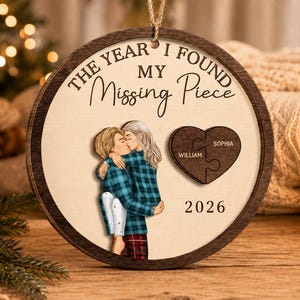 以下が含まれることがあります： THE YEAR I FOUND MY Missing Pieceという文字、抱き合うカップルのイラスト、WilliamとSophiaの名前が刻印されたハート型のパズルピース、そして2026という年号がプリントされた円形の木製オーナメント。