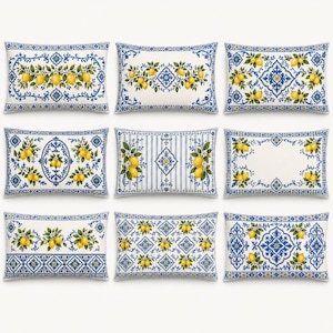 May include: A collection of nine rectangular throw pillows featuring various blue and white patterns with yellow lemon motifs and green leaves. The designs include intricate floral borders, geometric shapes, and vertical stripes on a white base.
