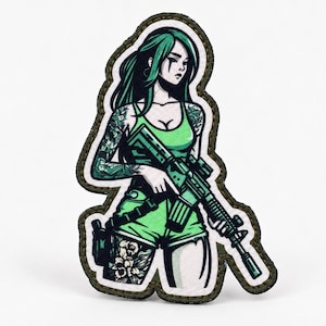 Op de afbeelding: Een gestanste geborduurde patch met een geïllustreerd personage met lang groen haar, gekleed in een groen hemdje en korte broek. Het personage heeft gedetailleerde tatoeages op armen en benen en houdt een zwart geweer vast. Donker olijfgroene rand.