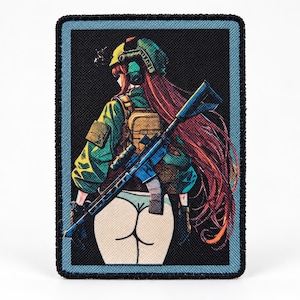Puede incluir: Un parche bordado rectangular que presenta un personaje de estilo anime con cabello largo y rojo, vistiendo una chaqueta táctica verde, un casco y una mochila. El personaje sostiene un rifle negro y se muestra de espaldas en ropa interior blanca.