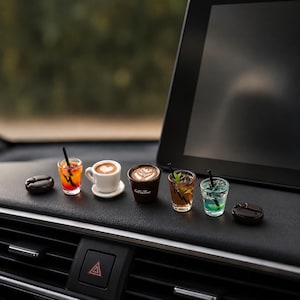 Peut inclure: Une collection de boissons miniatures comprenant une boisson rouge, une tasse à café blanche avec un cœur, une tasse brune marquée Coffee Time avec du latte art, une boisson ambrée à la menthe et une boisson bleue, entourées de deux grains de café.
