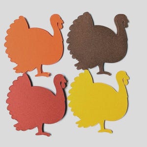May include: Four turkey-shaped paper cutouts arranged in a grid. The top left cutout is orange, the top right is dark brown, the bottom left is deep red, and the bottom right is yellow. Each cutout features a scalloped tail and a simple neck.