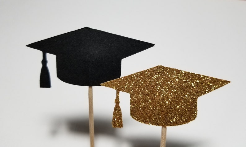 May include: Two graduation caps on sticks, one black and one gold glitter.