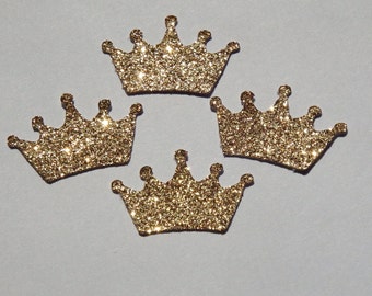 Op de afbeelding: Vier gouden glitterkronen, elk met een puntige top en vijf punten aan elke kant. De kronen bevinden zich op een witte achtergrond.