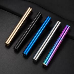 May include: Five cylindrical metal tubes arranged diagonally. The tubes feature a smooth finish in gold, black, blue, silver, and a multi-colored iridescent gradient. Each tube has a distinct cap section and a flat circular base at the bottom end.