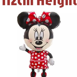 Może przedstawiać: Balon foliowy w kształcie Myszki Minnie, z czerwoną sukienką w białe kropki, pasującą czerwoną kokardą w białe kropki, czarnymi uszami i białymi rękawiczkami. Tekst 112cm Height znajduje się nad balonem, wskazując jego całkowitą wysokość.