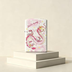 May include: A rectangular metal lighter featuring a light pink and white gradient background with the text Hello Kitty in cursive. The design includes a long, winding pink dragon and three small Hello Kitty characters with wings and stars.