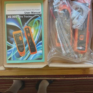 May include: An open box containing a network wire tracker kit. The kit includes a user manual, two orange and black wire trackers, and other components. The user manual reads "Multi-purpose Communication Network Wire Tracker User Manual XQ-350 Wire Tracker."