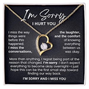 Könnte beinhalten: Eine goldfarbene herzförmige Anhängerkette mit einem zentralen Zirkonia-Stein, präsentiert auf einer schwarzen Karte mit dem aufgedruckten Text: I'm Sorry I Hurt You, I miss the way things were before this happened, I miss the conversations, the laughter, and the comfort of knowing everything between us was okay. More than anything, I regret being part of the reason that changed. I'm sorry. I don't expect everything to become okay overnight—I just hope this can be the first small step toward finding our way back. I'M SORRY AND I MISS YOU.
